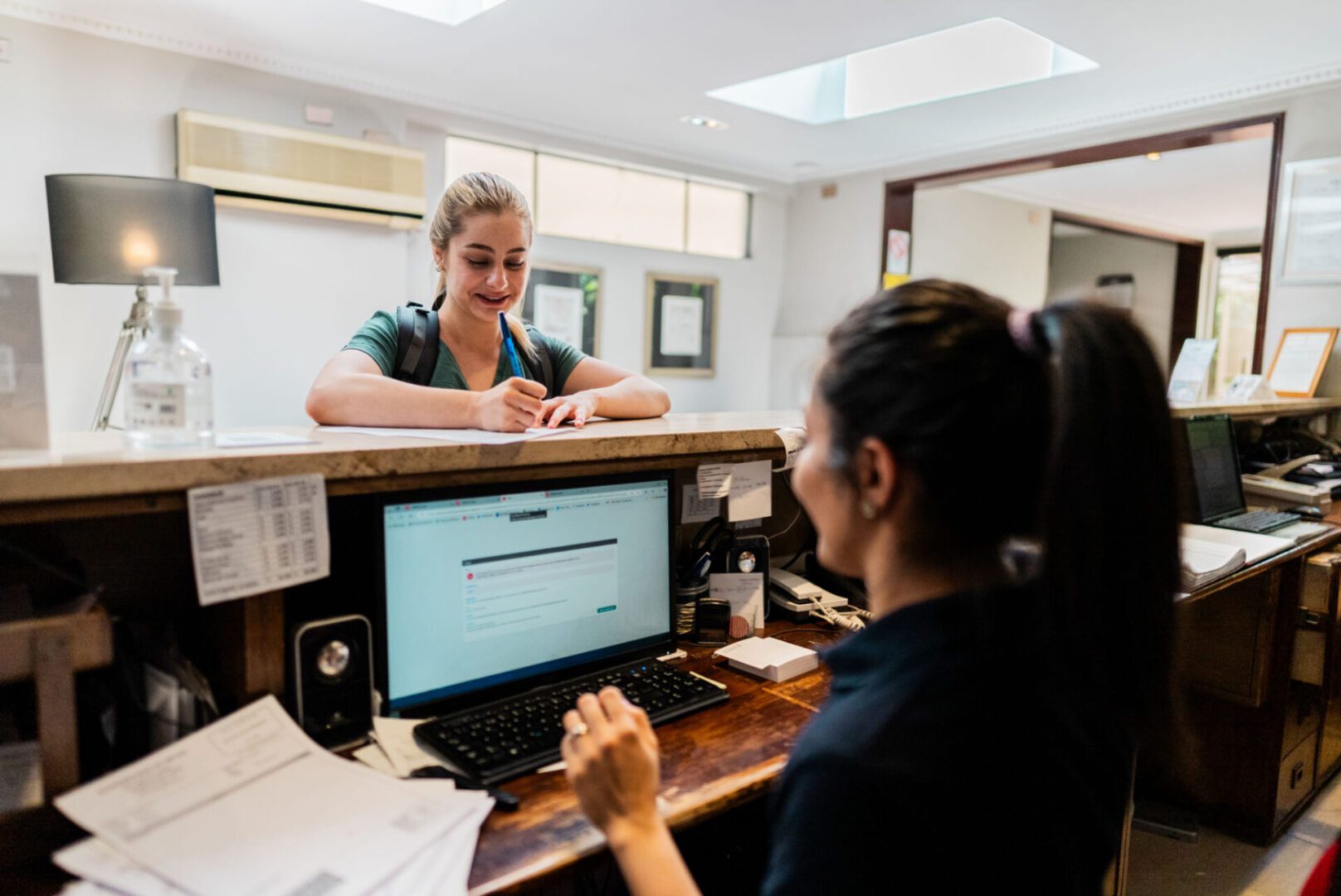 Receptionist assisting a guest at counter.